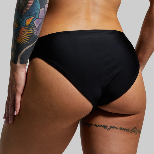 Woman wearing black bikini bottom with a neutral background