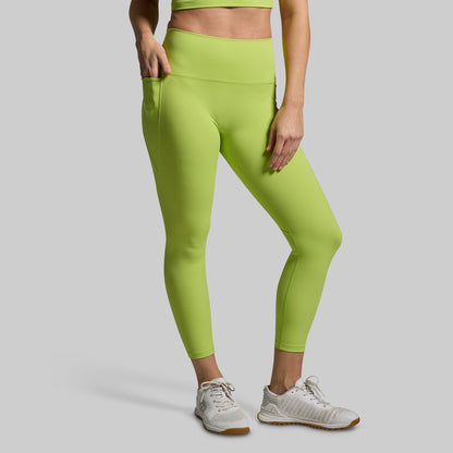 Person wearing bright green leggings and white sneakers on a gray background