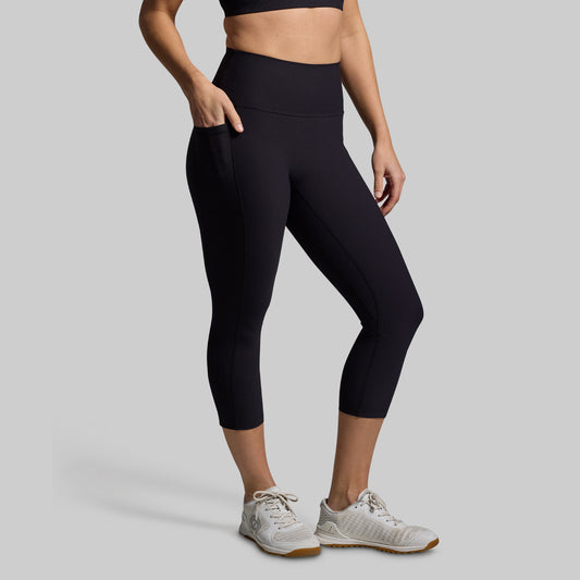 Person wearing black leggings and white sneakers on a gray background