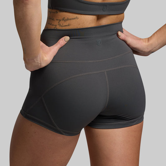 Person wearing dark gray athletic shorts on a gray background