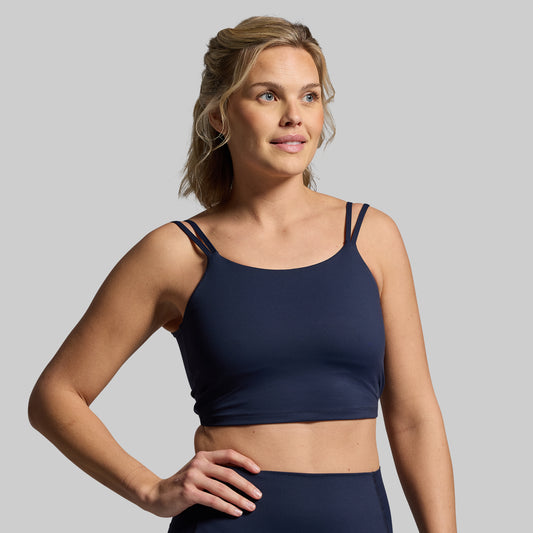 Woman wearing a navy blue sports bra on a gray background
