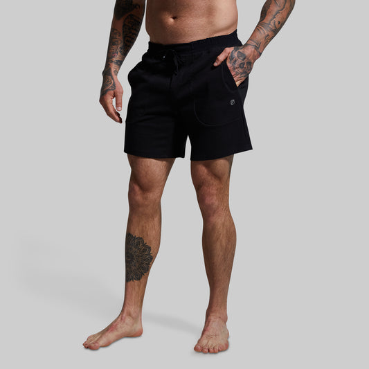 A male model wearing black lounge shorts with a textured surface, standing against a plain background.