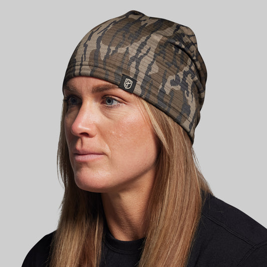 Person wearing a camouflage beanie against a plain background