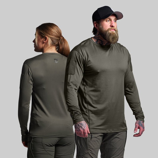 Two people wearing olive green long-sleeve shirts and pants on a gray background
