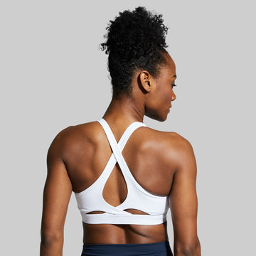Woman wearing a white sports bra against a gray background