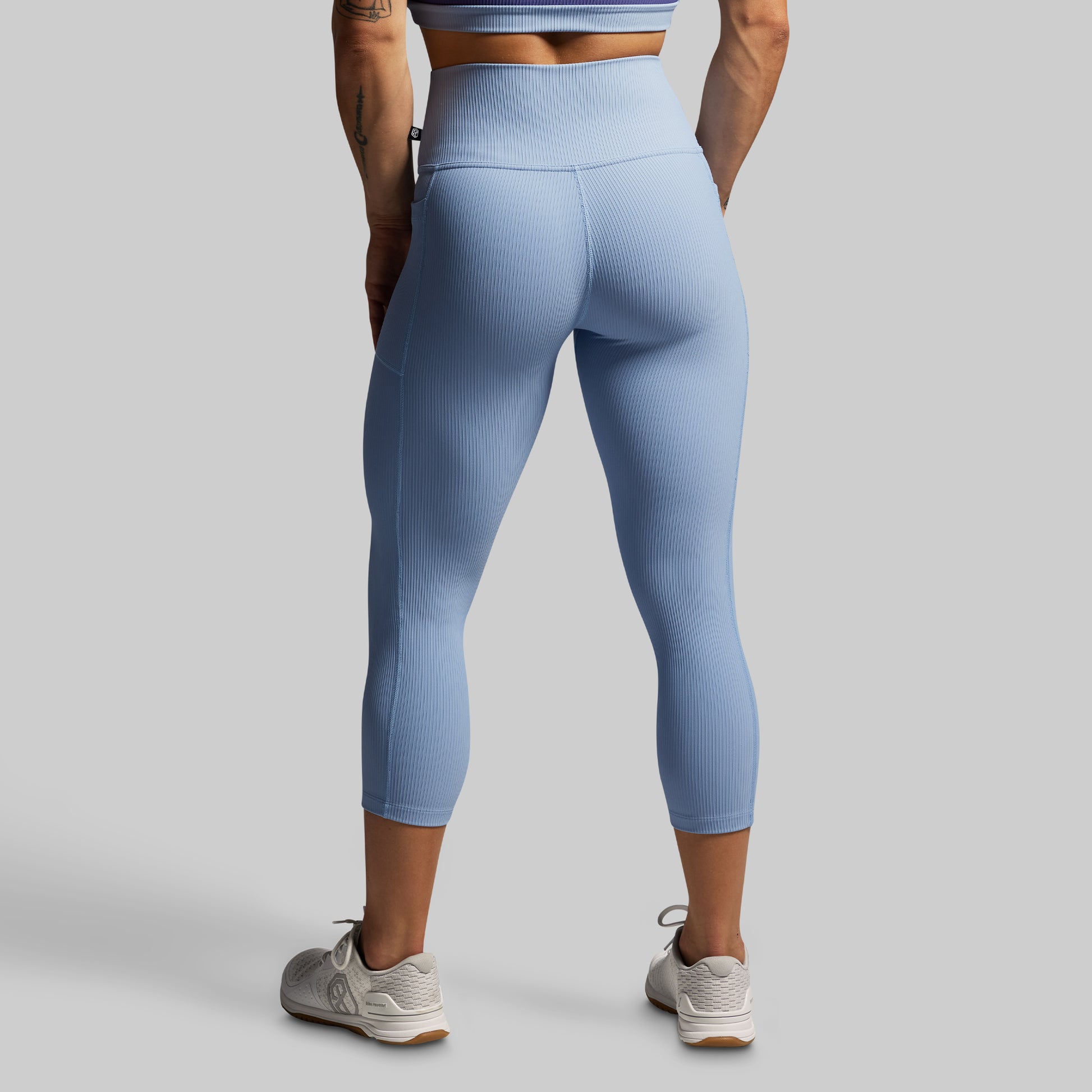 Person wearing light blue leggings on a gray background