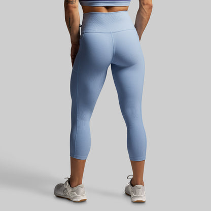 Person wearing light blue leggings on a gray background