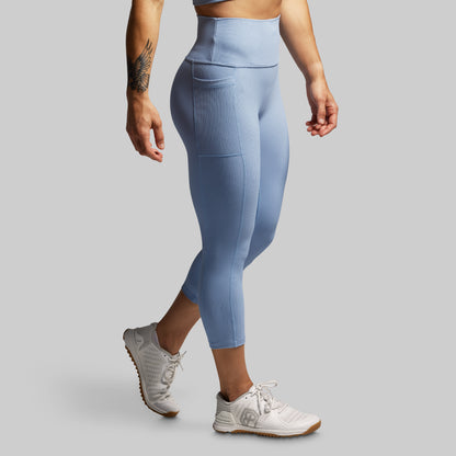Person wearing light blue leggings and white sneakers on a gray background