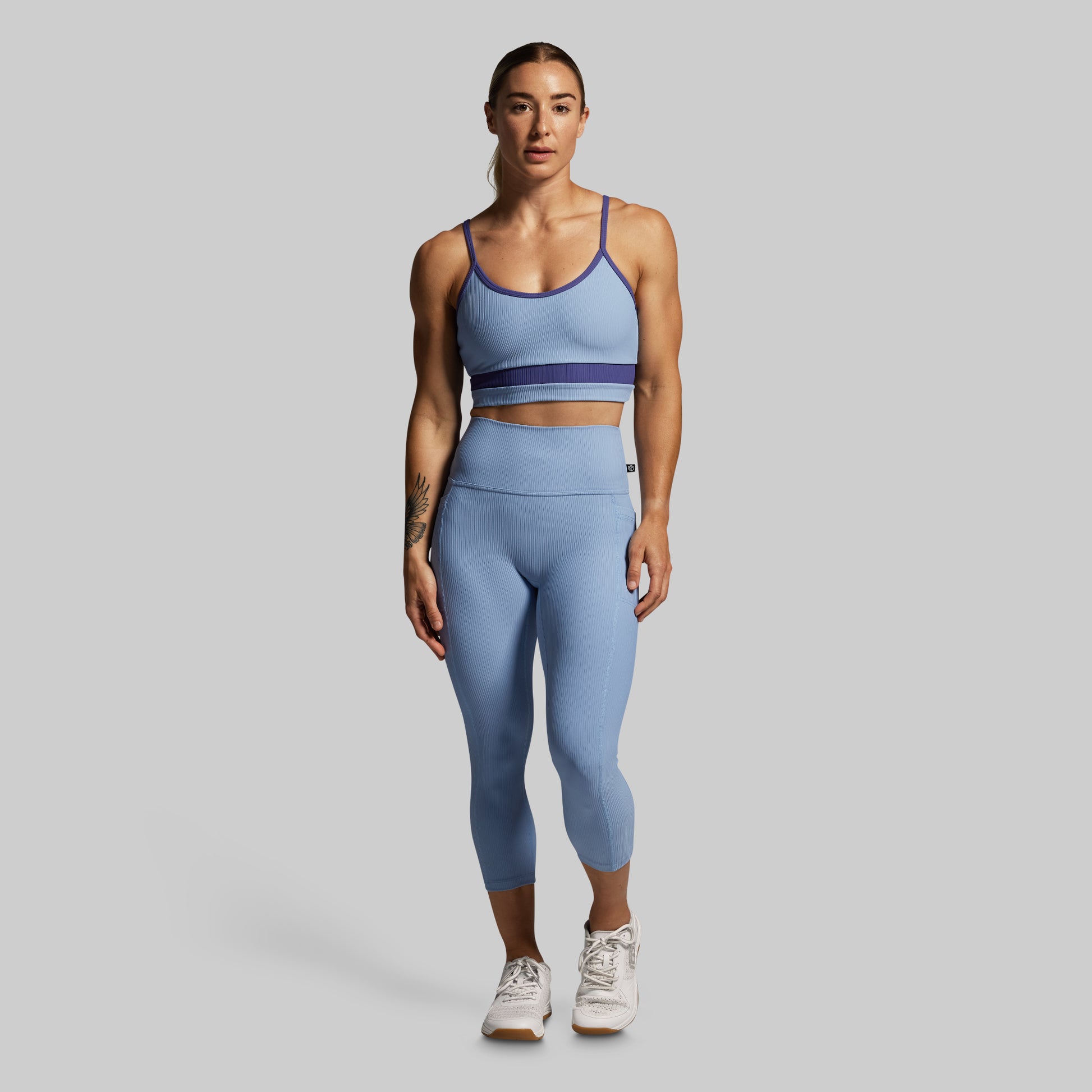 Woman wearing a blue athletic outfit on a gray background