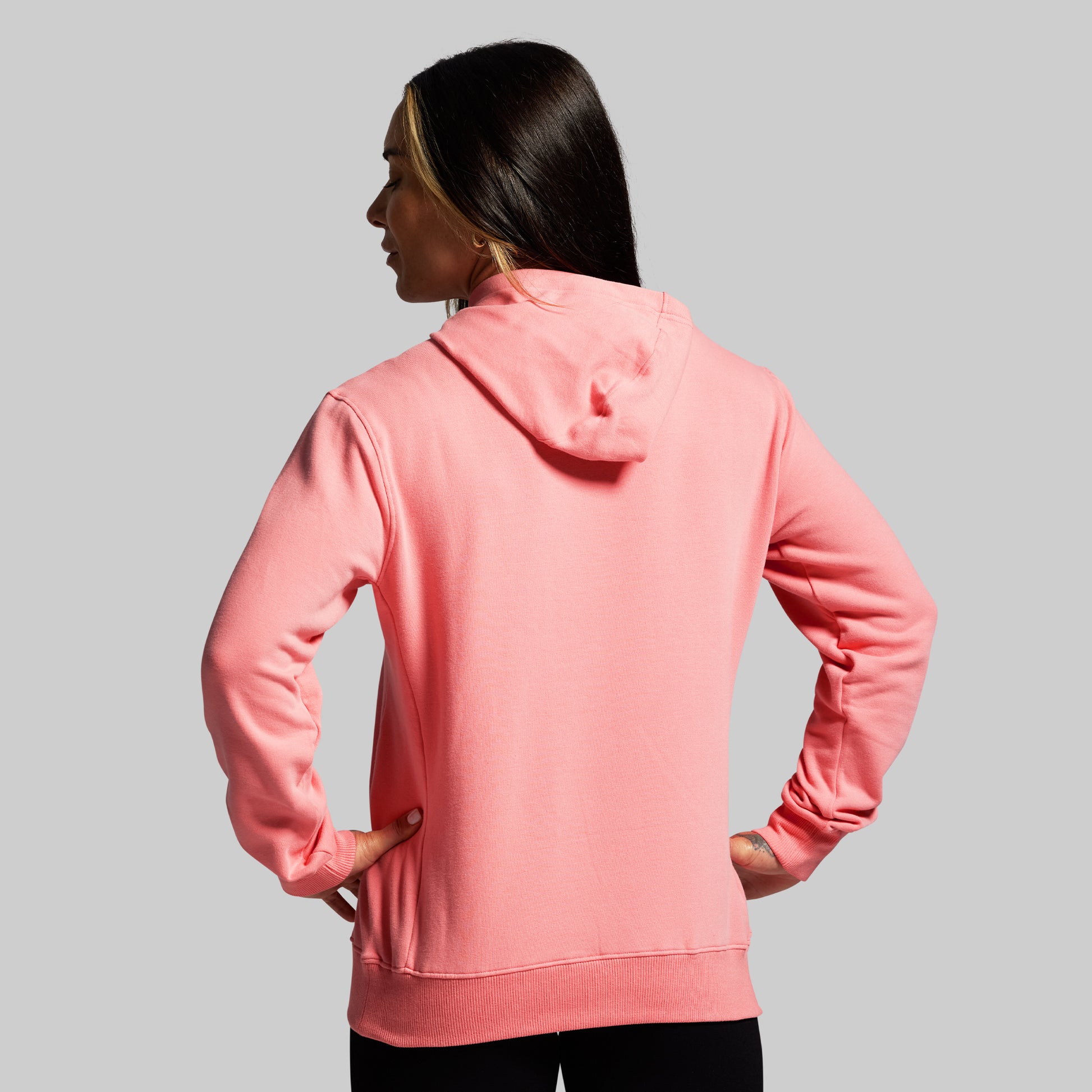 Person wearing a pink hoodie on a gray background