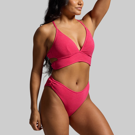 Woman wearing a pink bikini against a gray background