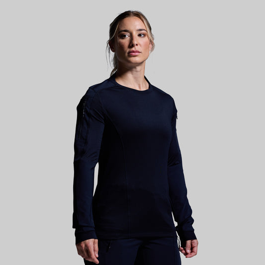 Woman wearing a dark blue long-sleeve tactical top against a gray background