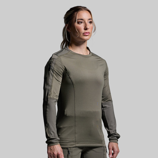 Woman wearing a green tactical long sleeve on a gray background