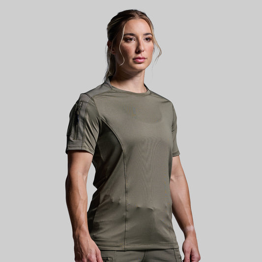 Woman wearing a green tactical shirt against a gray background