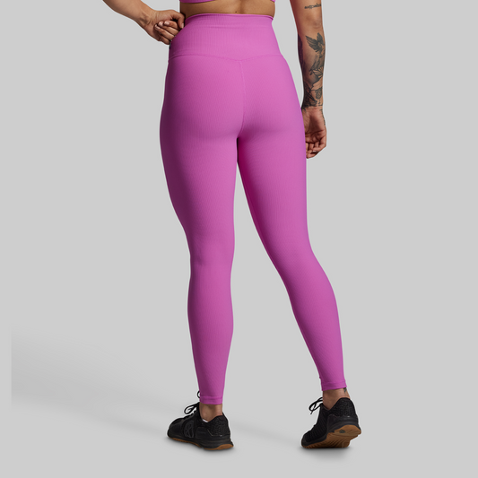 Person wearing bright pink leggings on a gray background