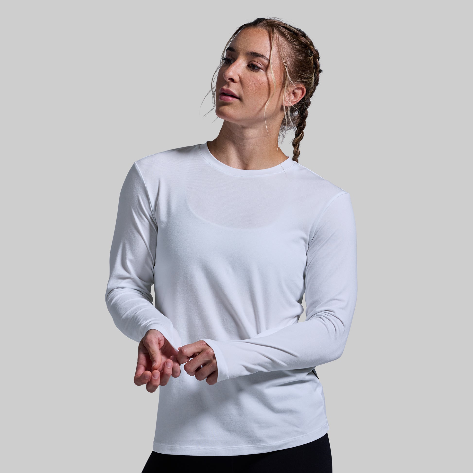 Woman wearing a white long-sleeve shirt against a plain background