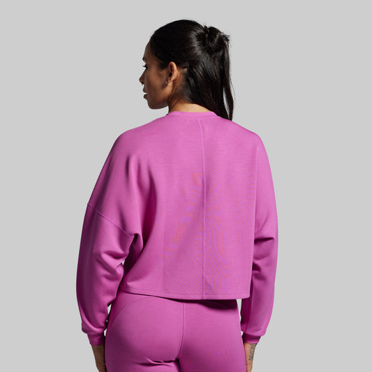 Person wearing a pink sweatshirt and pants on a gray background