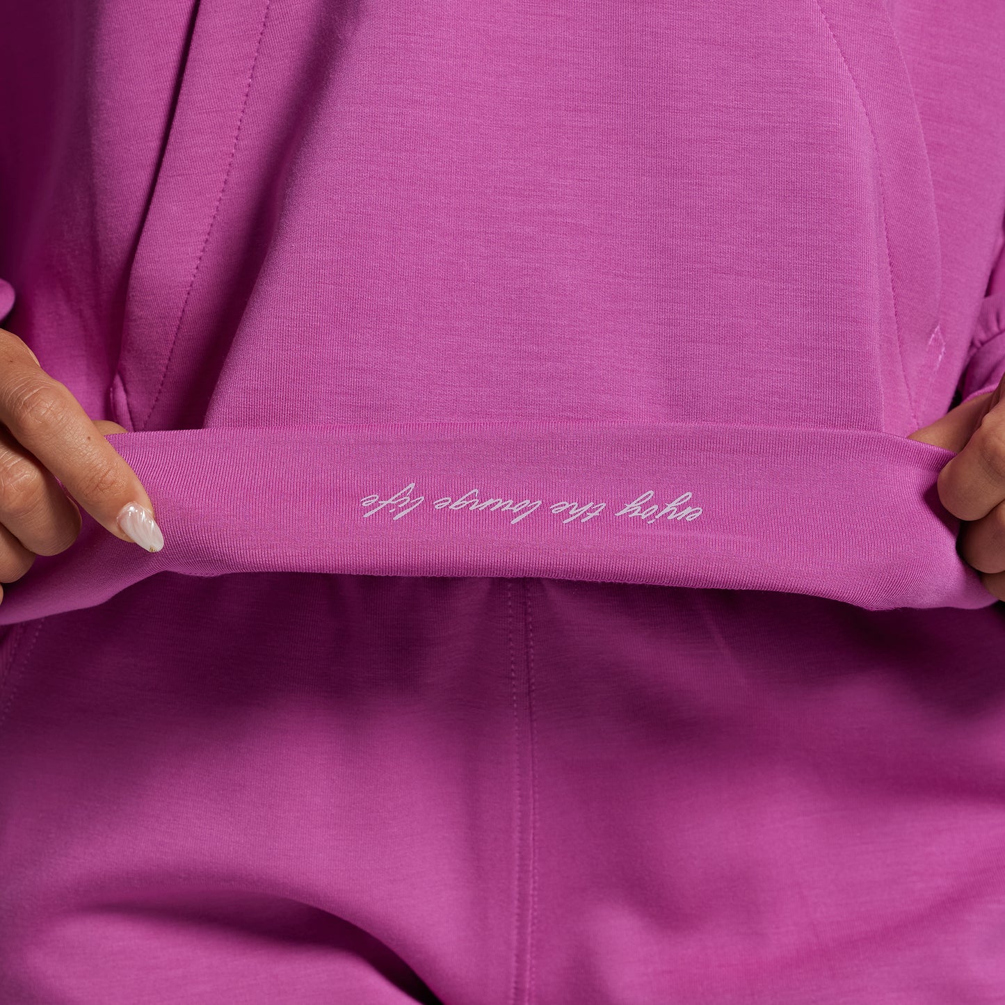 Close-up of a pink garment with text on it, held by hands.