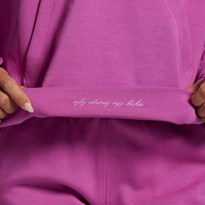 Close-up of a pink garment with text on it, held by hands.