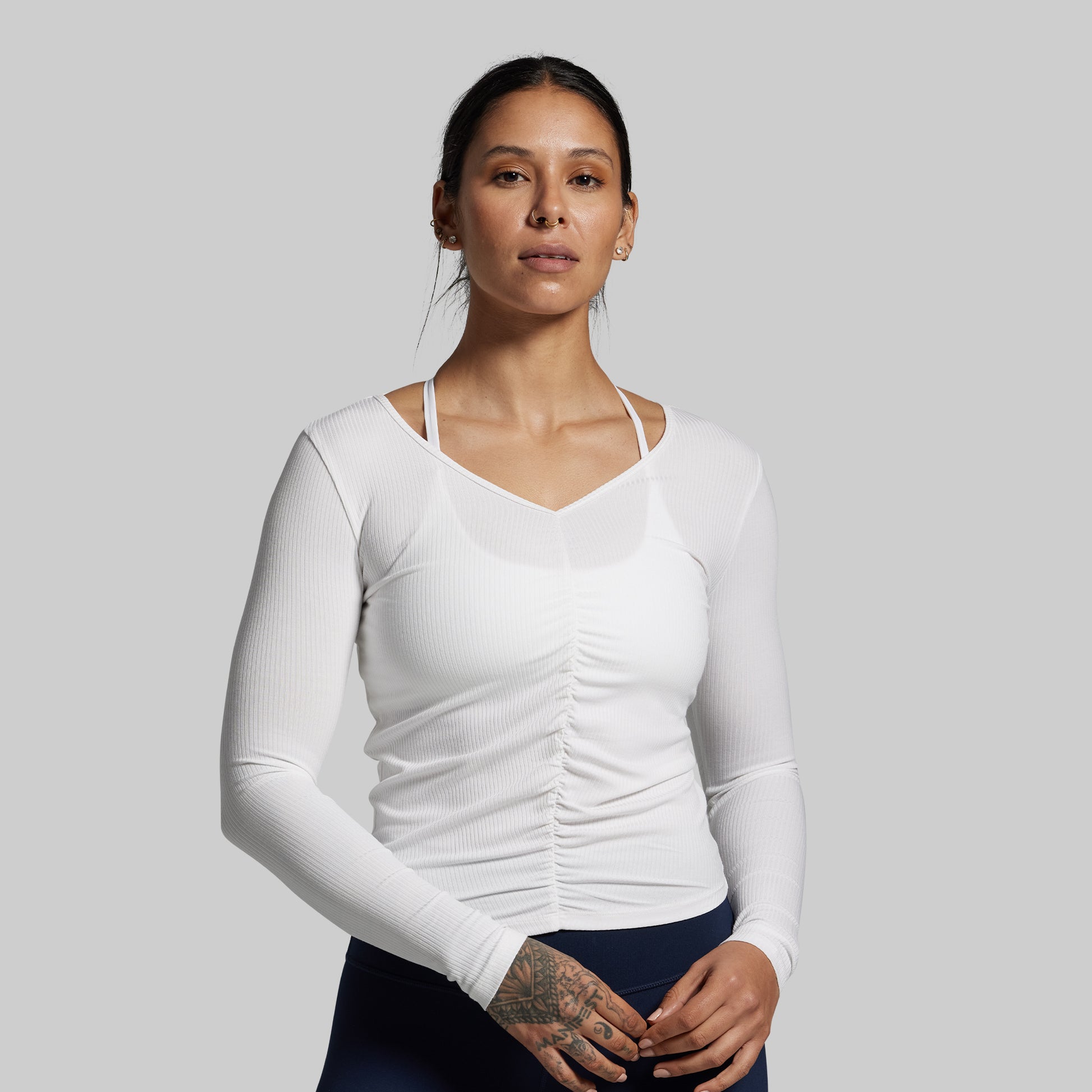 Woman wearing a white long-sleeve athletic top against a gray background