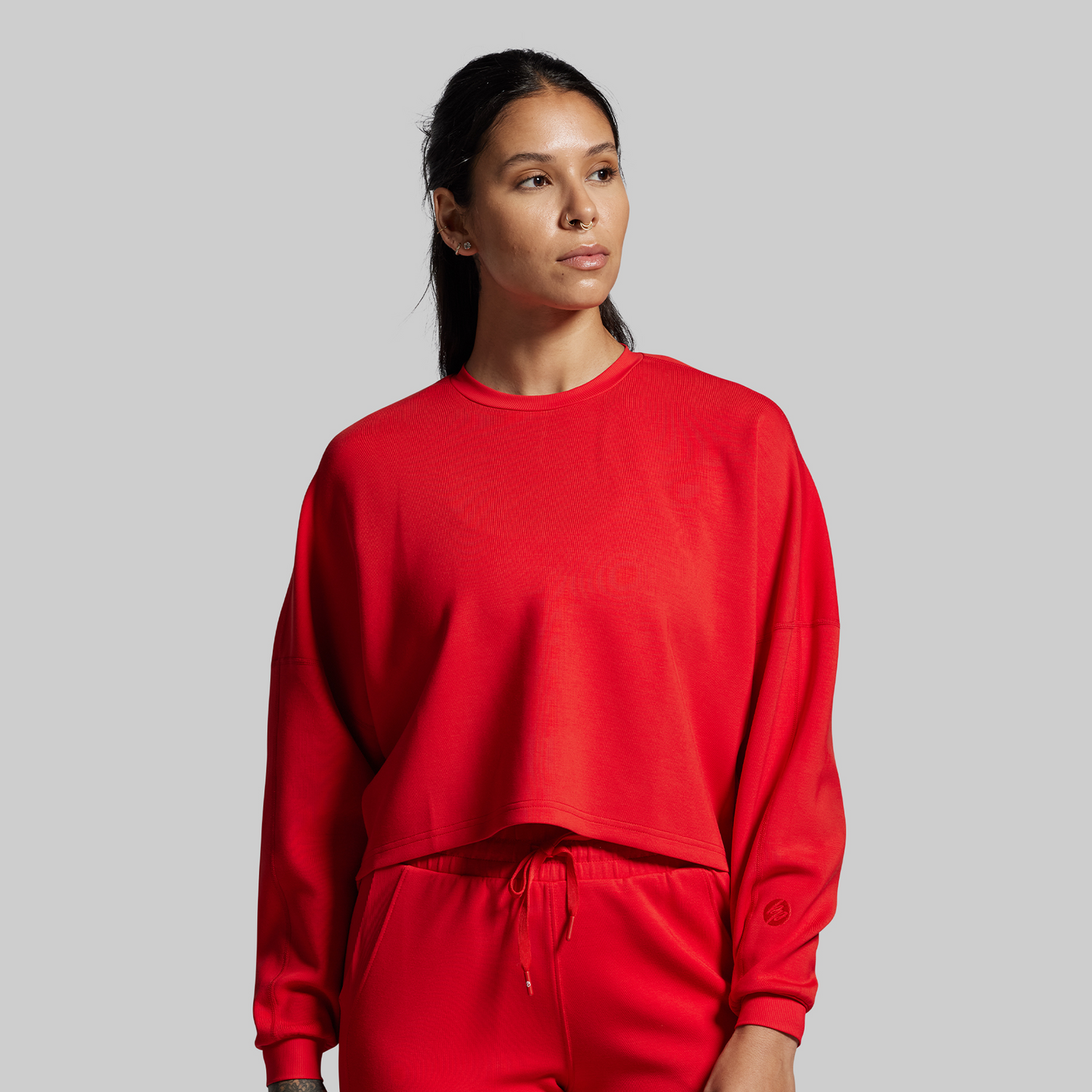 Person wearing a red sweatshirt and pants on a gray background