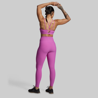 Person wearing a pink sports bra and leggings set on a gray background