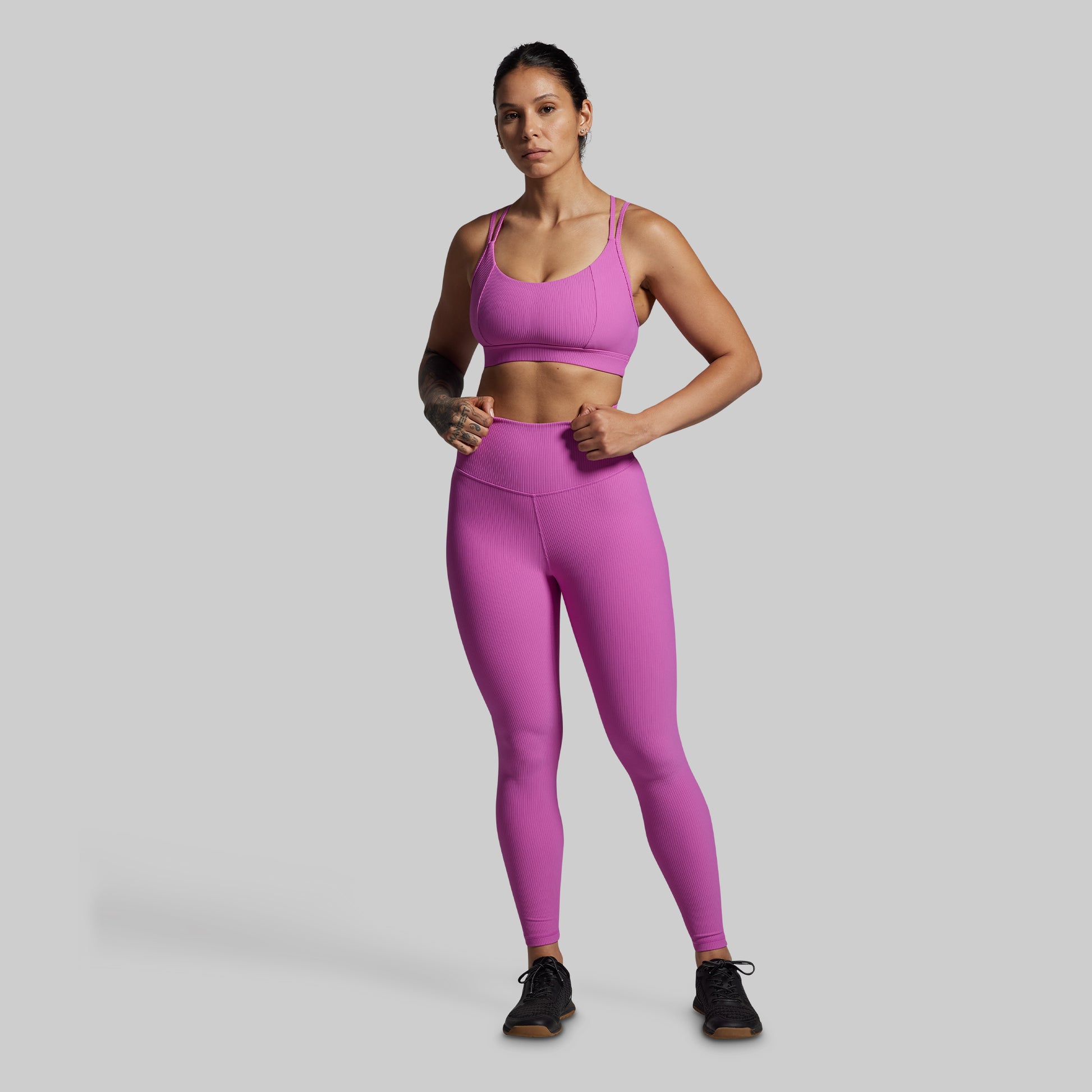 Woman wearing a pink athletic outfit on a gray background