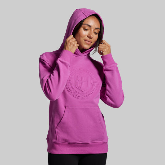 Person wearing a purple hoodie with a logo on a gray background