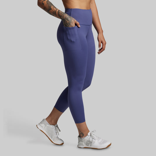 Person wearing blue leggings and white sneakers on a gray background