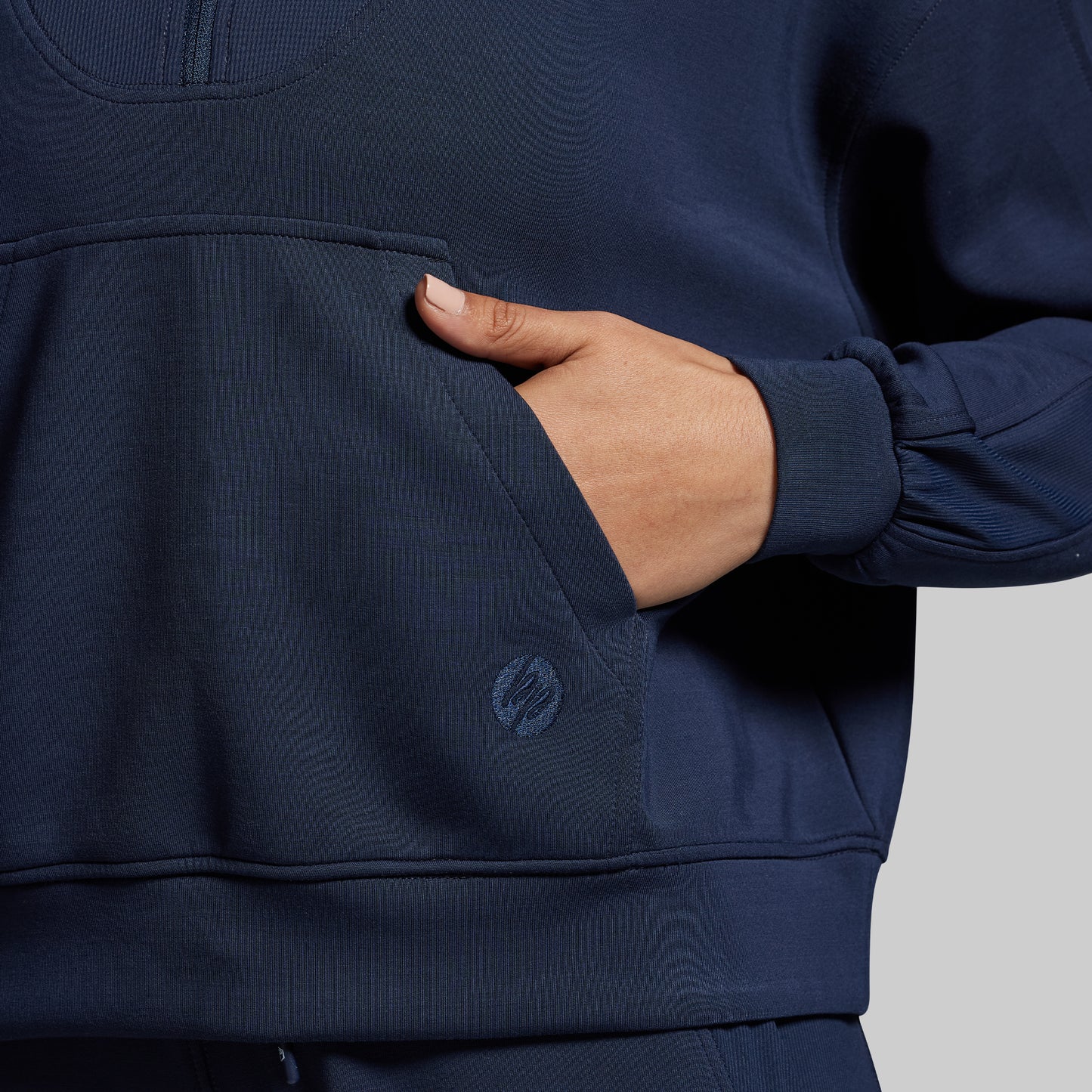 Navy blue pullover with a brand logo on a gray background