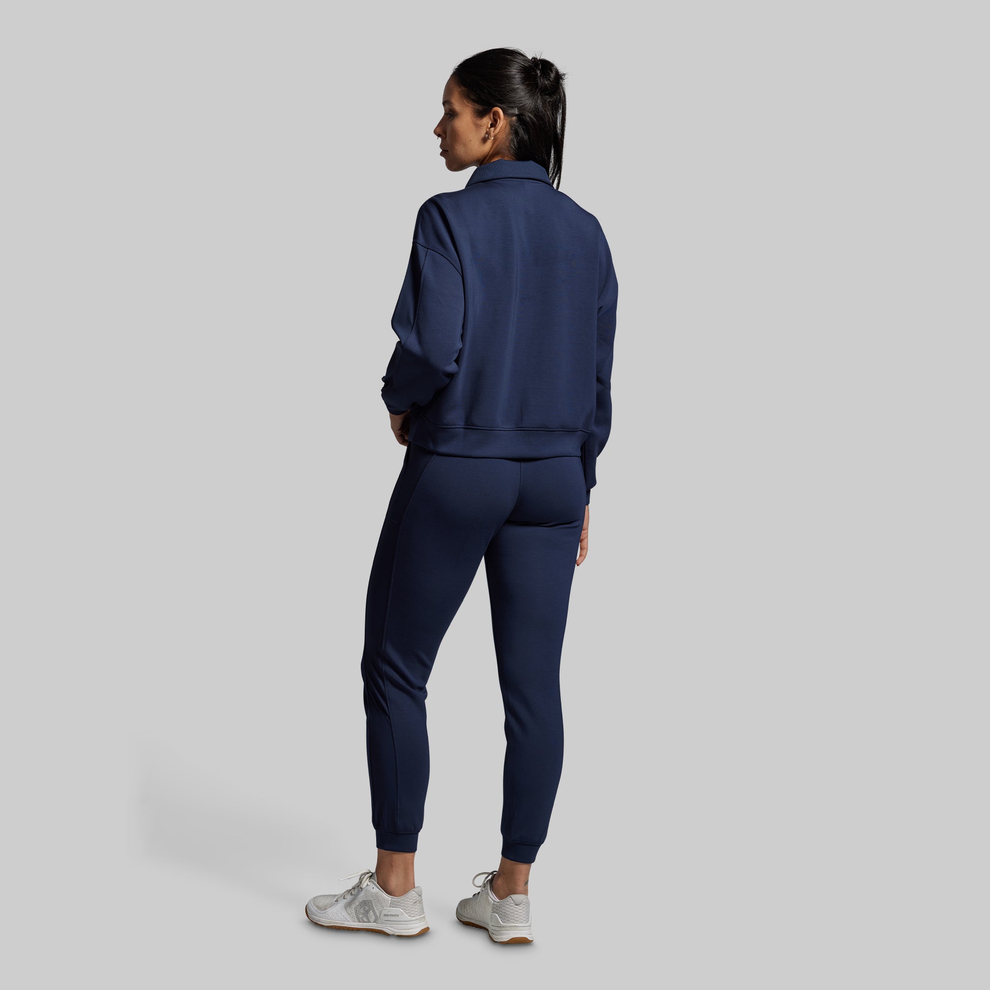 Person wearing a navy tracksuit on a light gray background