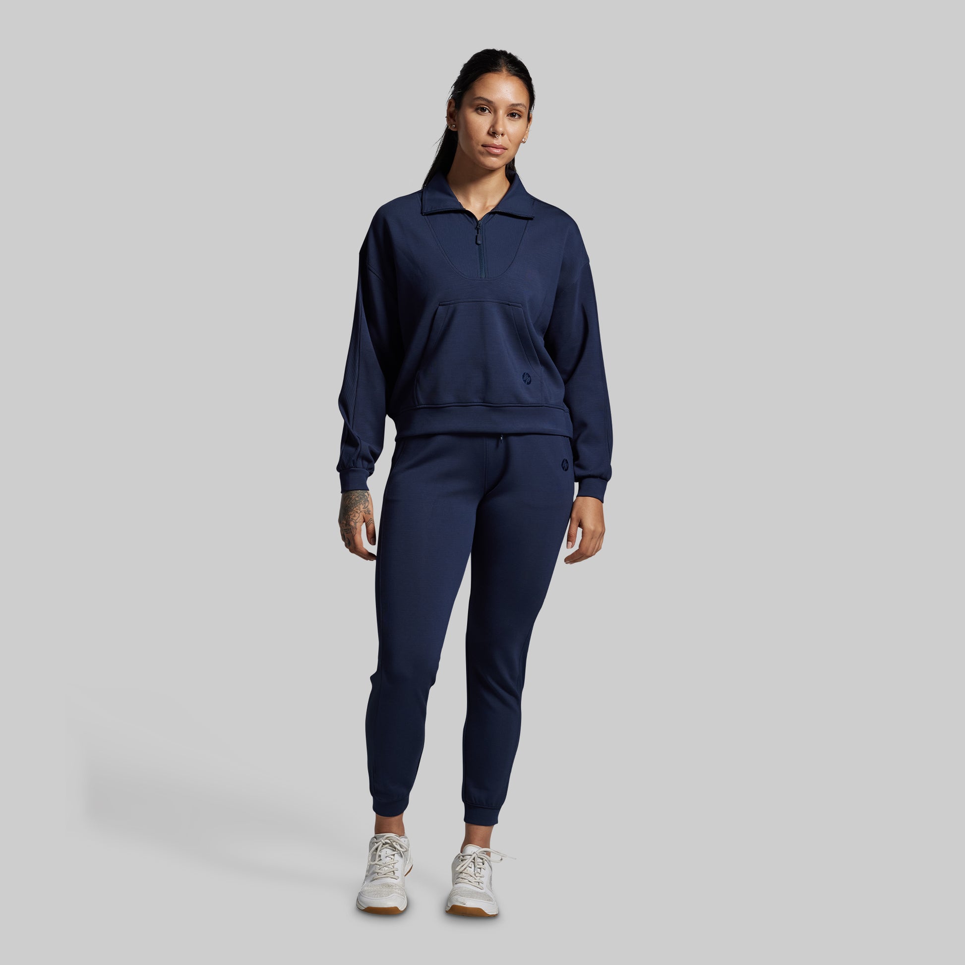 Person wearing a navy blue tracksuit on a gray background