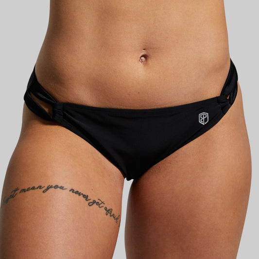 Black bikini bottom worn by a person on a plain background