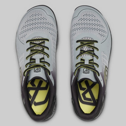 Pair of gray athletic shoes with yellow accents on a light gray background