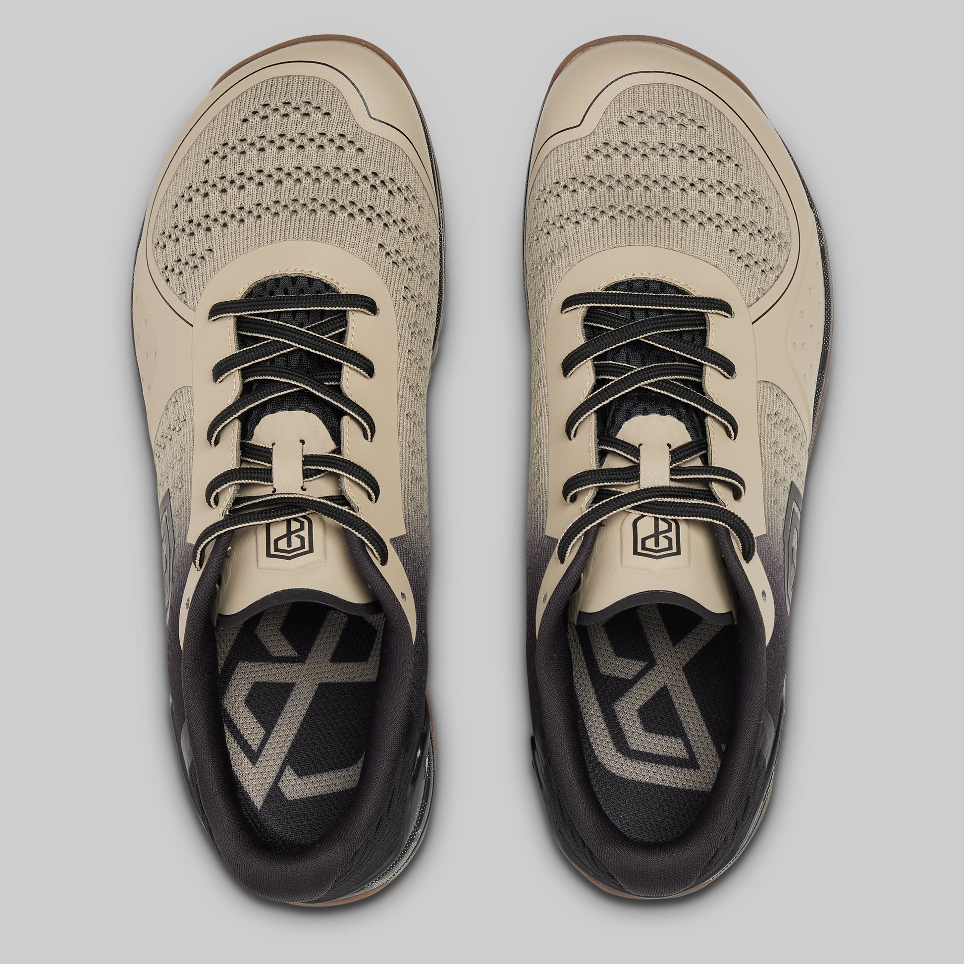 Pair of beige and black athletic shoes on a light gray background