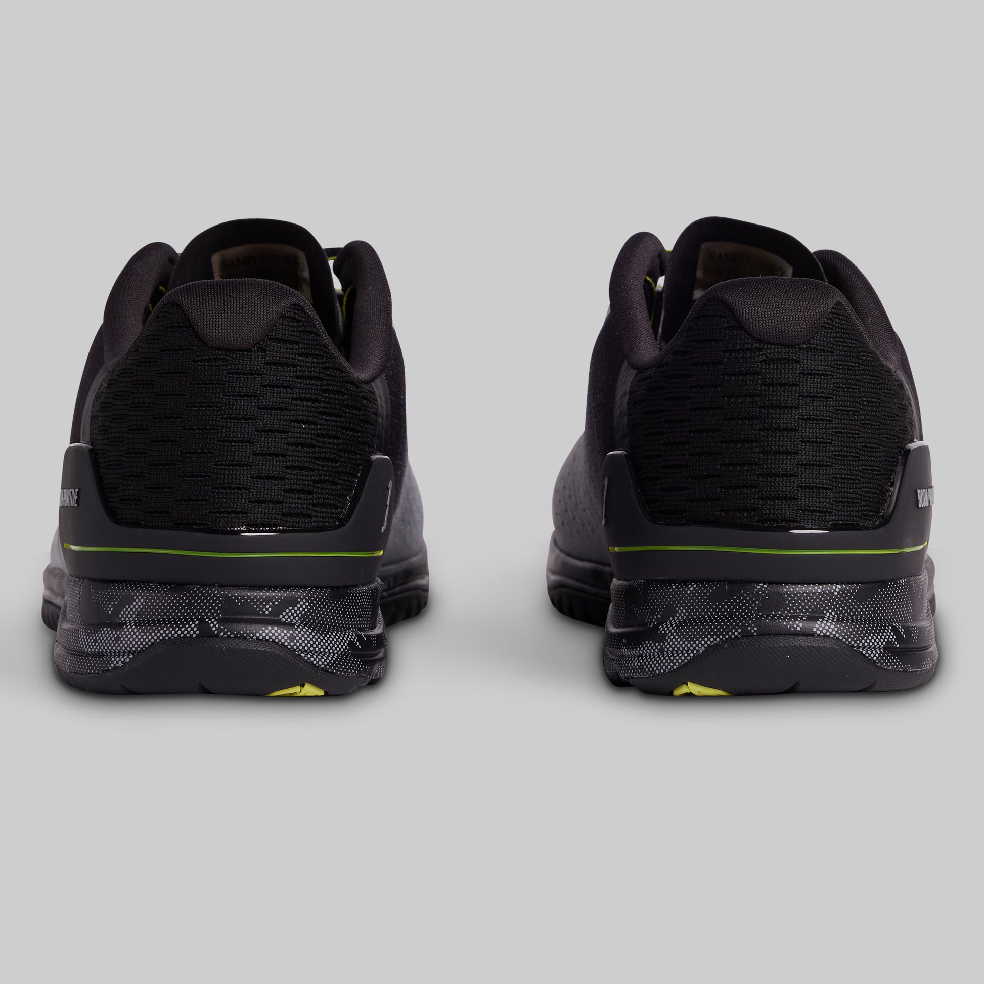Black athletic shoes with green accents on a light gray background