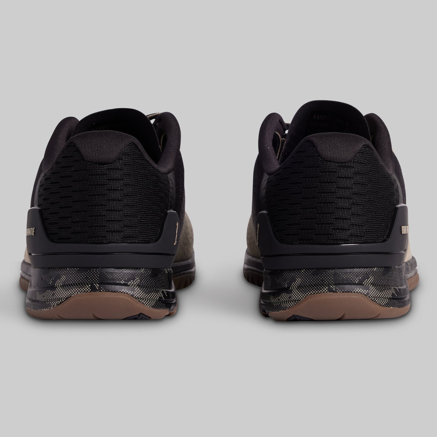 Black athletic shoes with brown soles on a light gray background