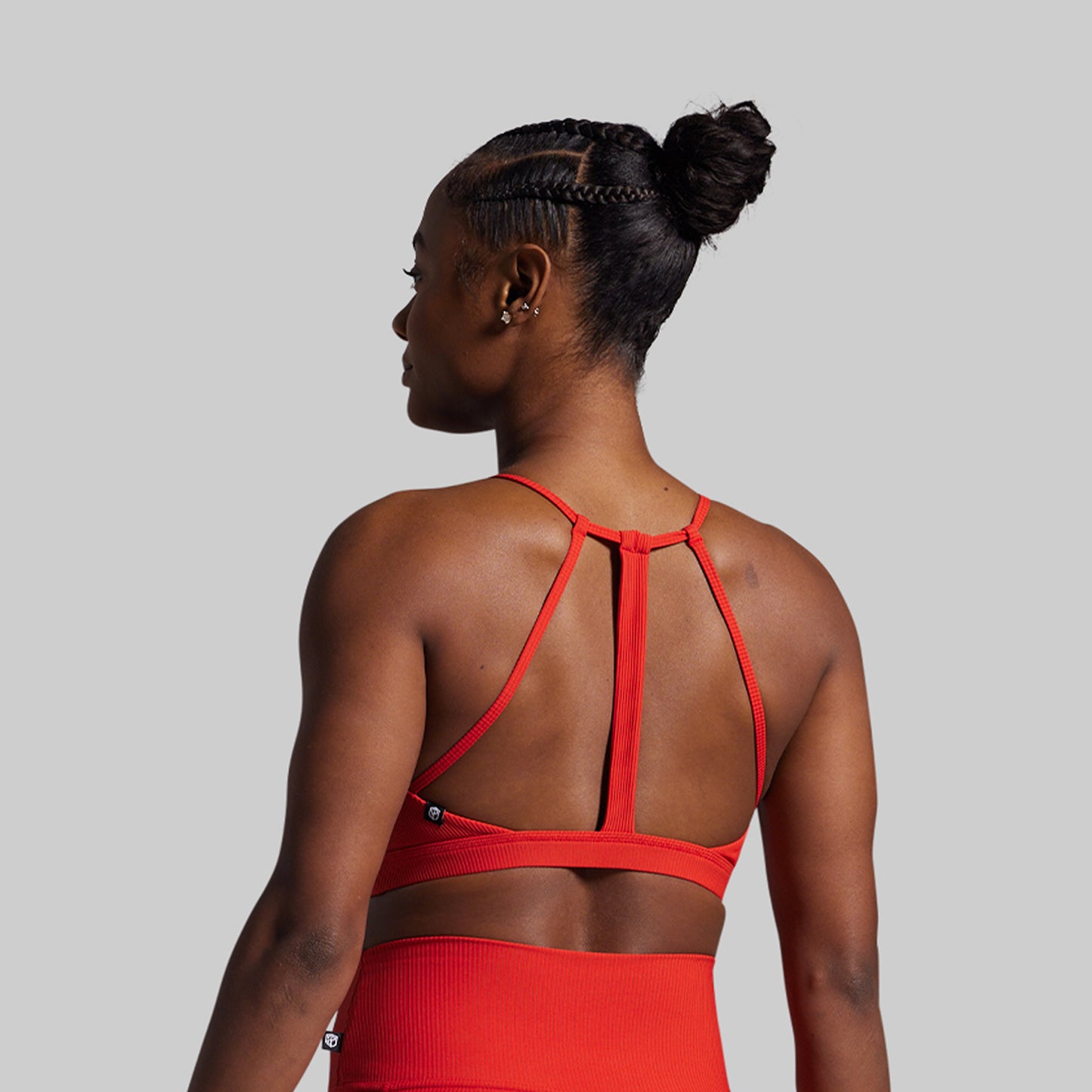 Person wearing a red sports bra and leggings on a gray background