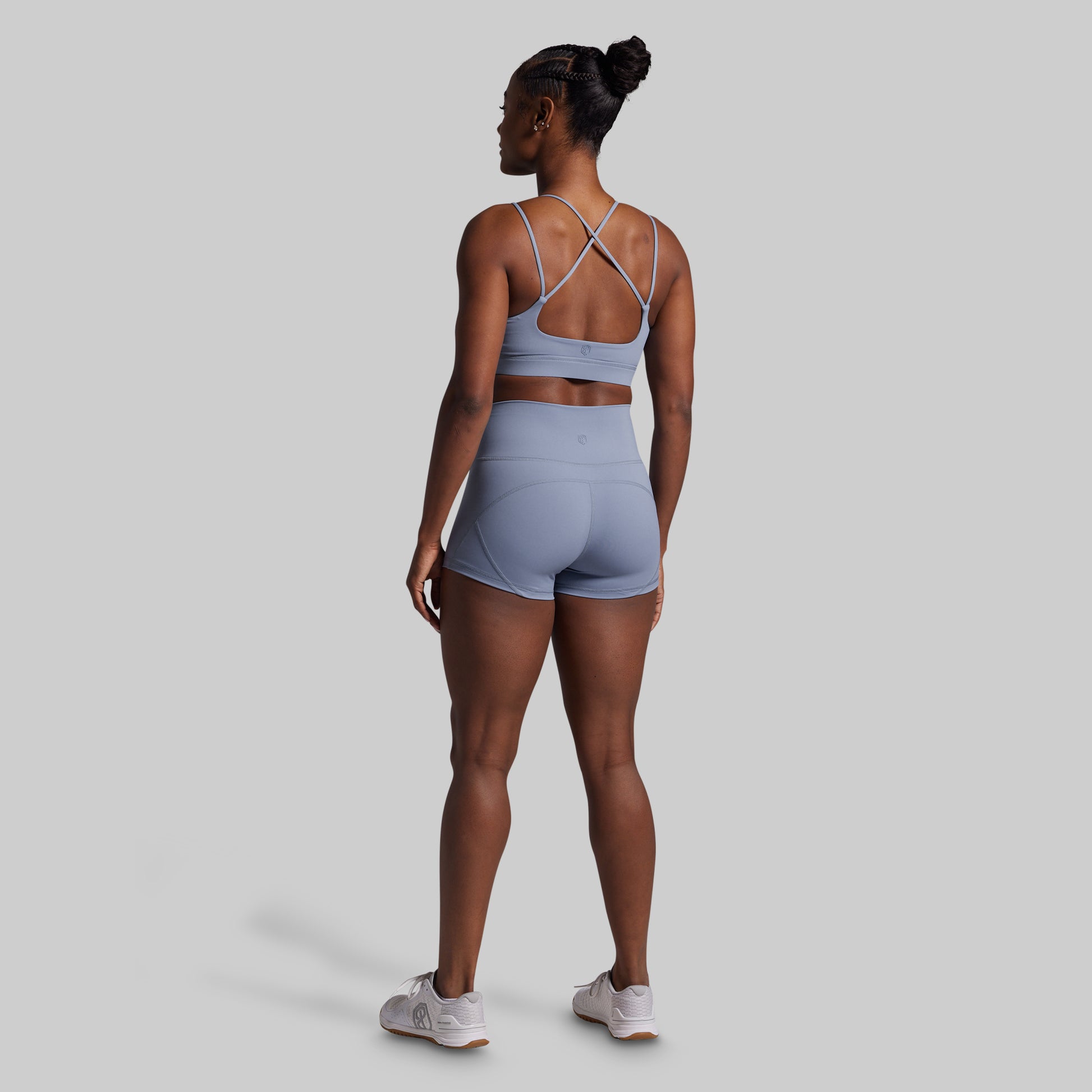 Woman wearing a light blue sports bra and shorts set on a gray background