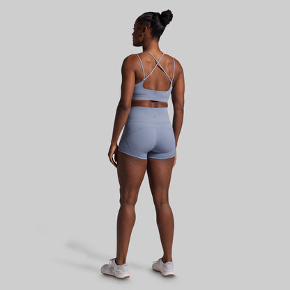 Woman wearing a light blue sports bra and shorts set on a gray background