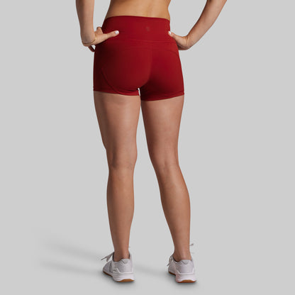 Person wearing red athletic shorts on a plain background