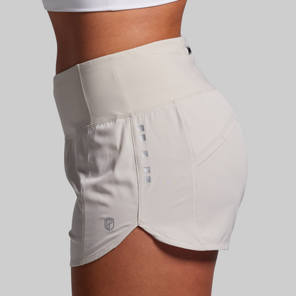 Beige athletic shorts with a brand logo on a light gray background