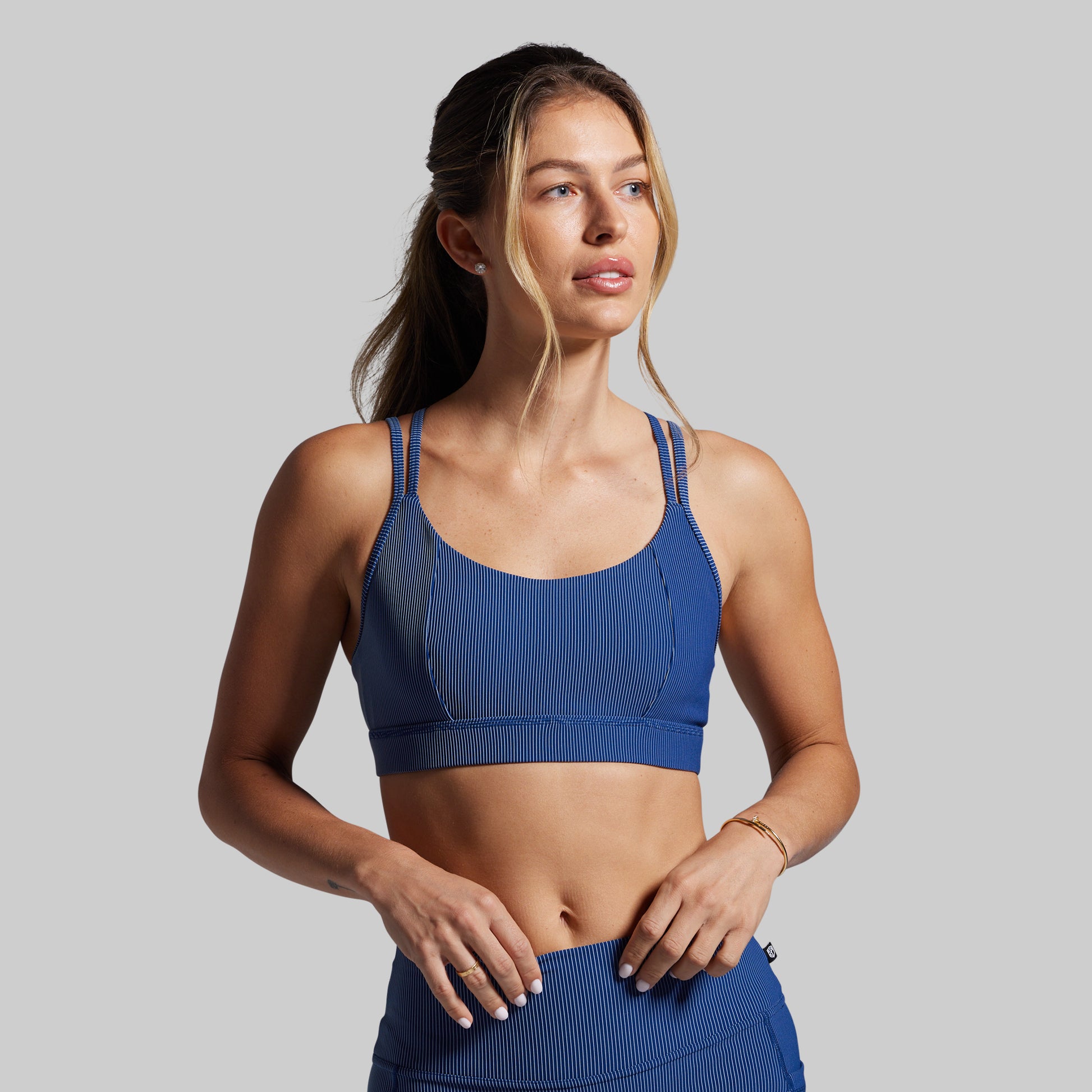 Woman wearing a blue sports bra and shorts on a gray background