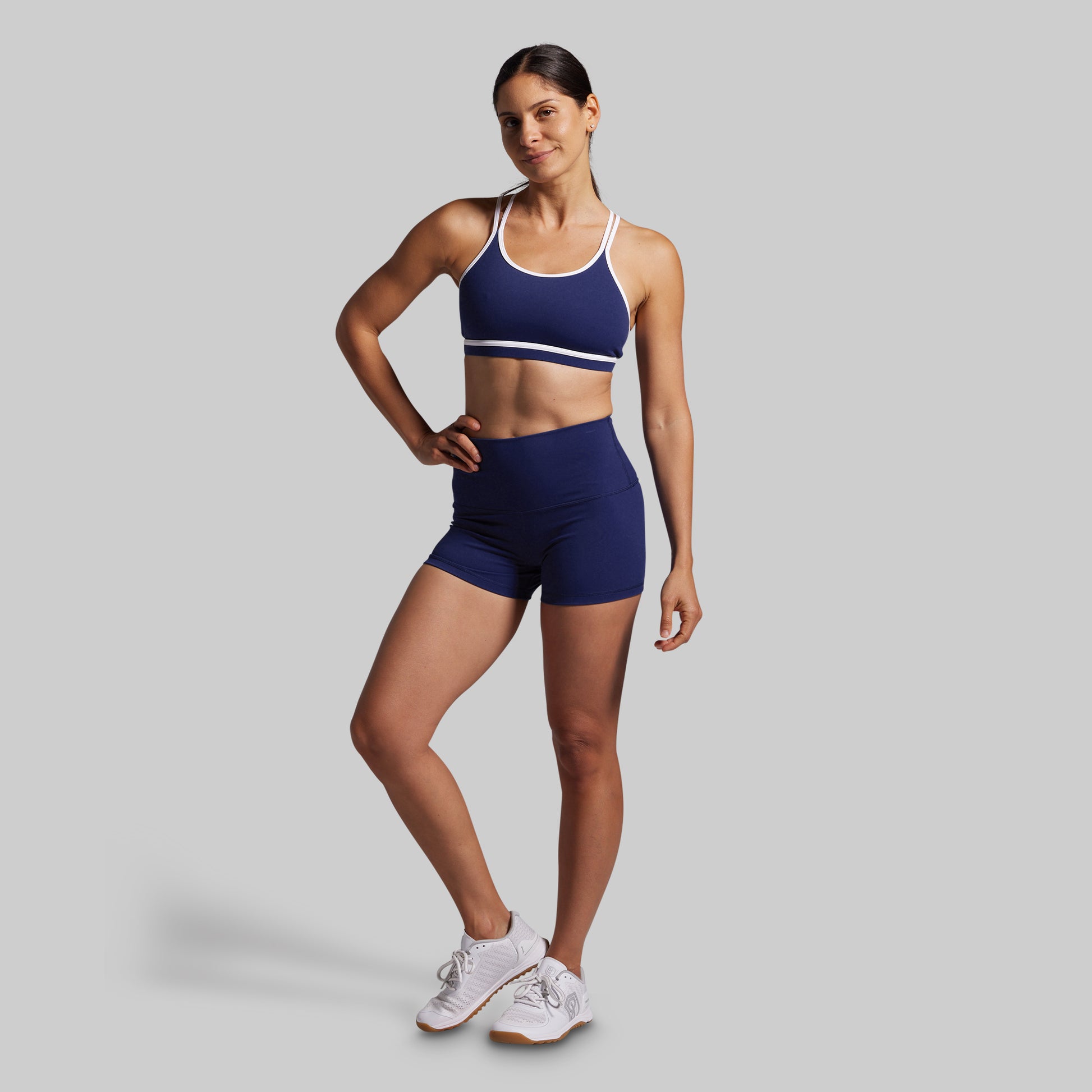 Woman wearing a blue sports bra and shorts set on a gray background