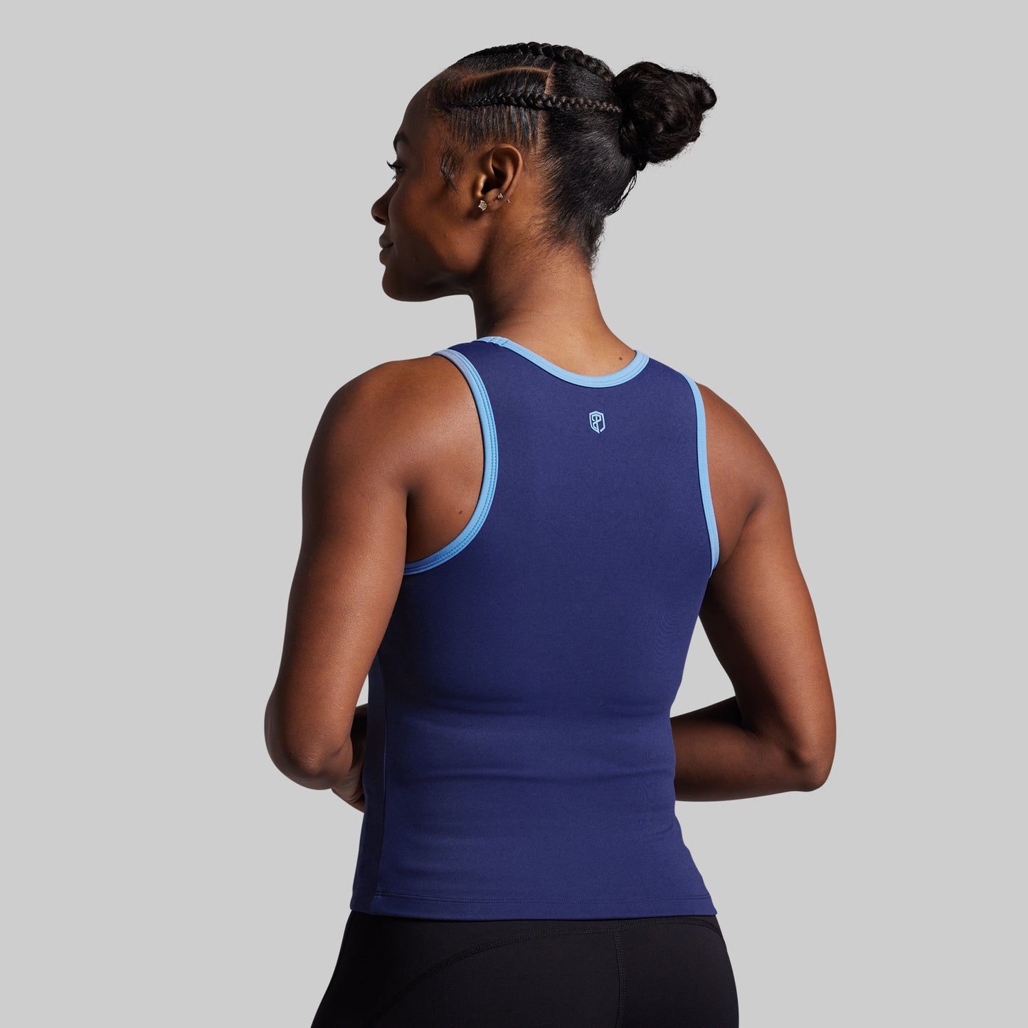 Woman wearing a blue athletic tank top on a gray background