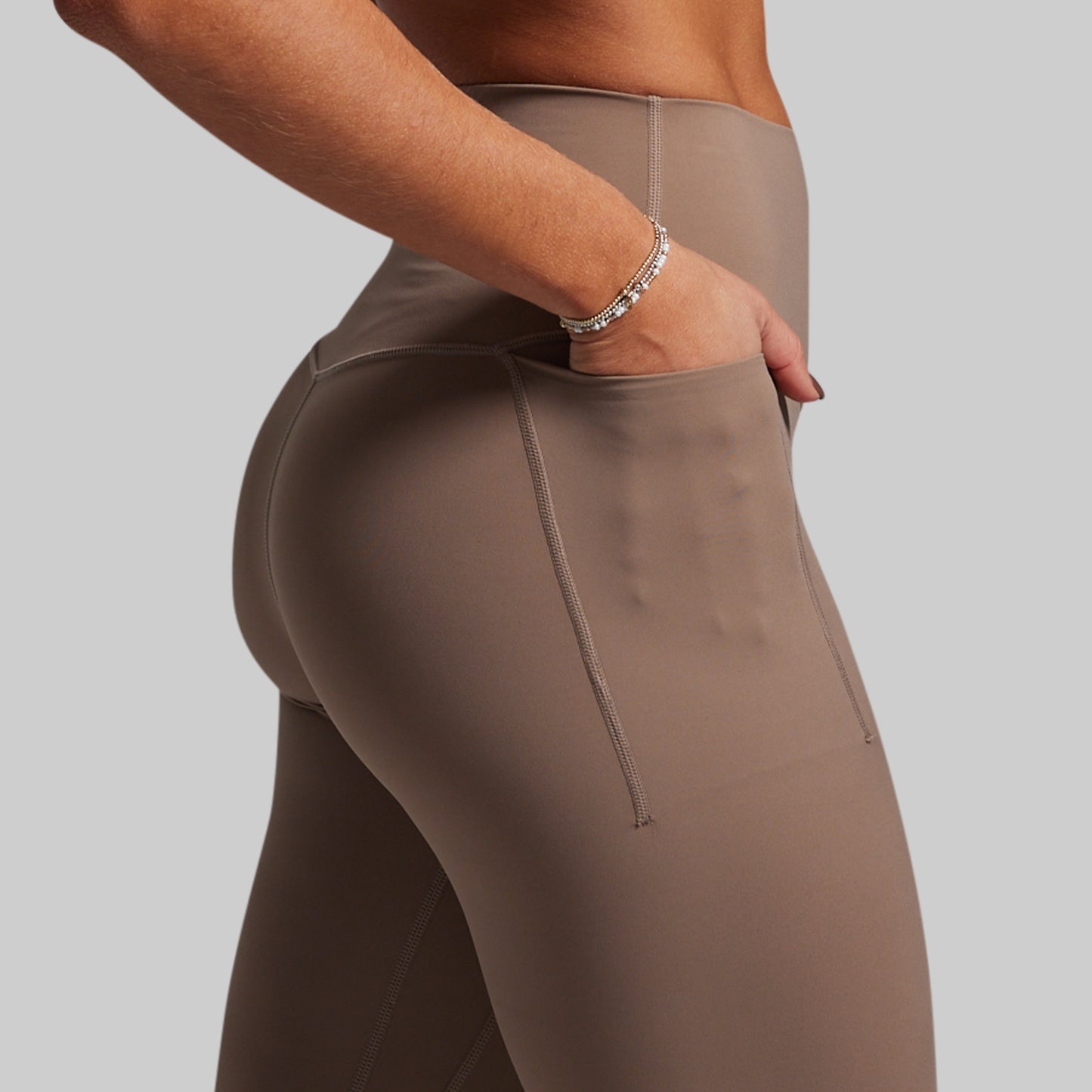 Brown leggings worn by a person on a gray background
