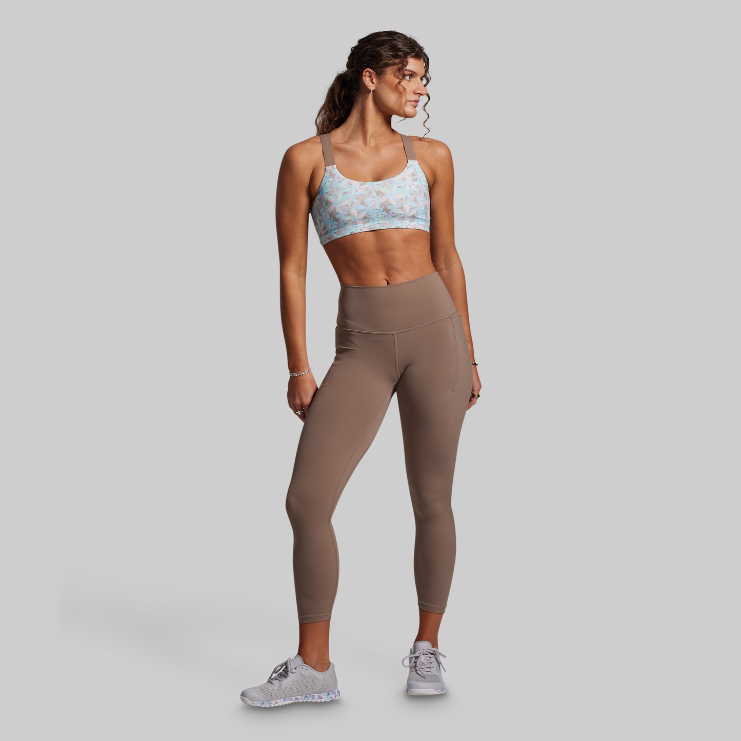 Woman wearing a sports bra and leggings on a gray background