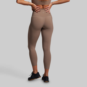 Person wearing brown leggings on a gray background