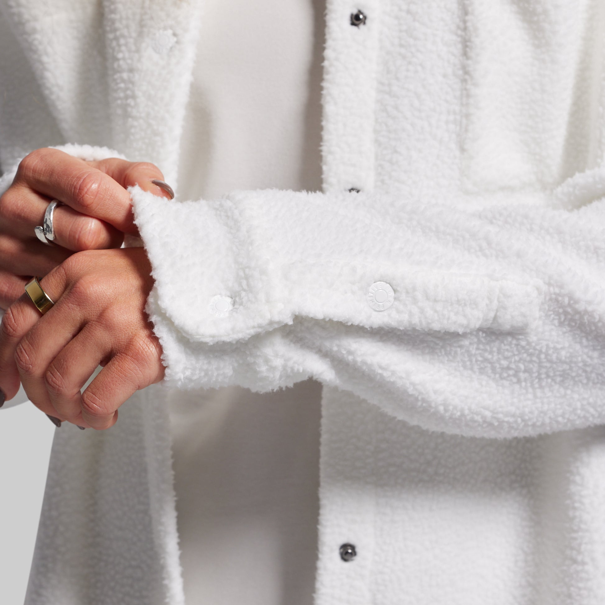 Close-up of a person wearing a white textured shirt with a neutral background