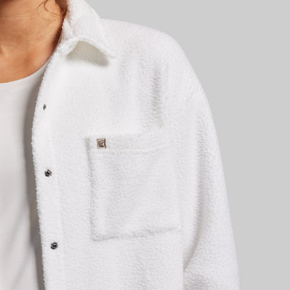 Close-up of a white sherpa jacket with buttons on a gray background